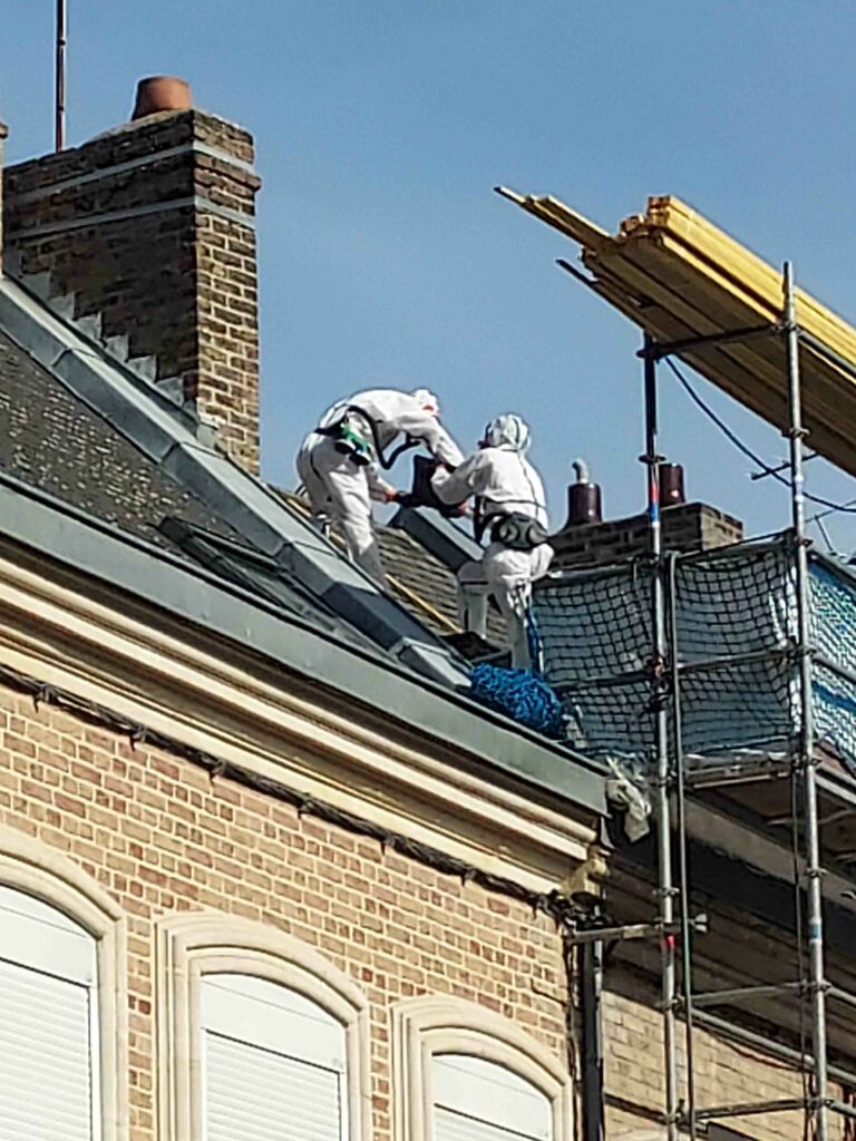 Couvreurs de l'Entreprise Caux en combinaison de protection lors d'un désamiantage de toiture à Amiens
